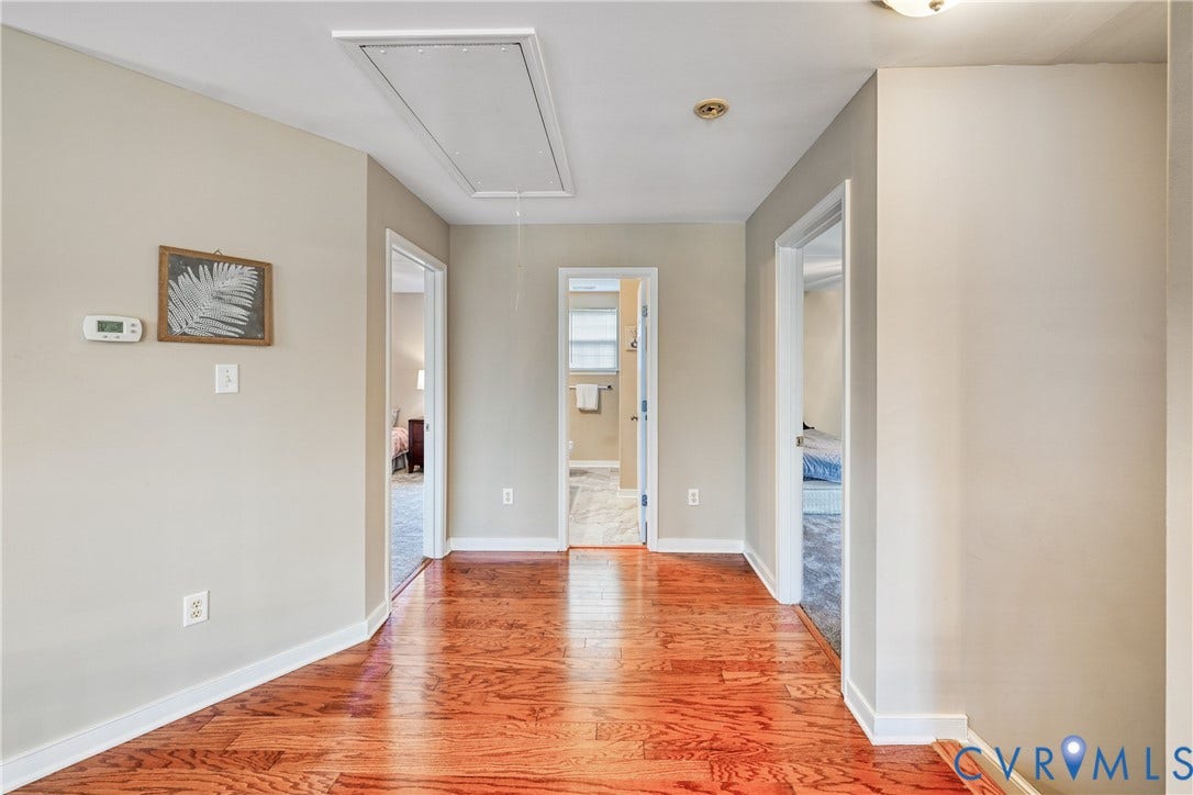 519 N Timber Tribe, Lake Anna, Mineral, VA 23117 Hallway featuring wood flooring, light neutral wall paint, white baseboards, and multiple doorways leading to additional rooms