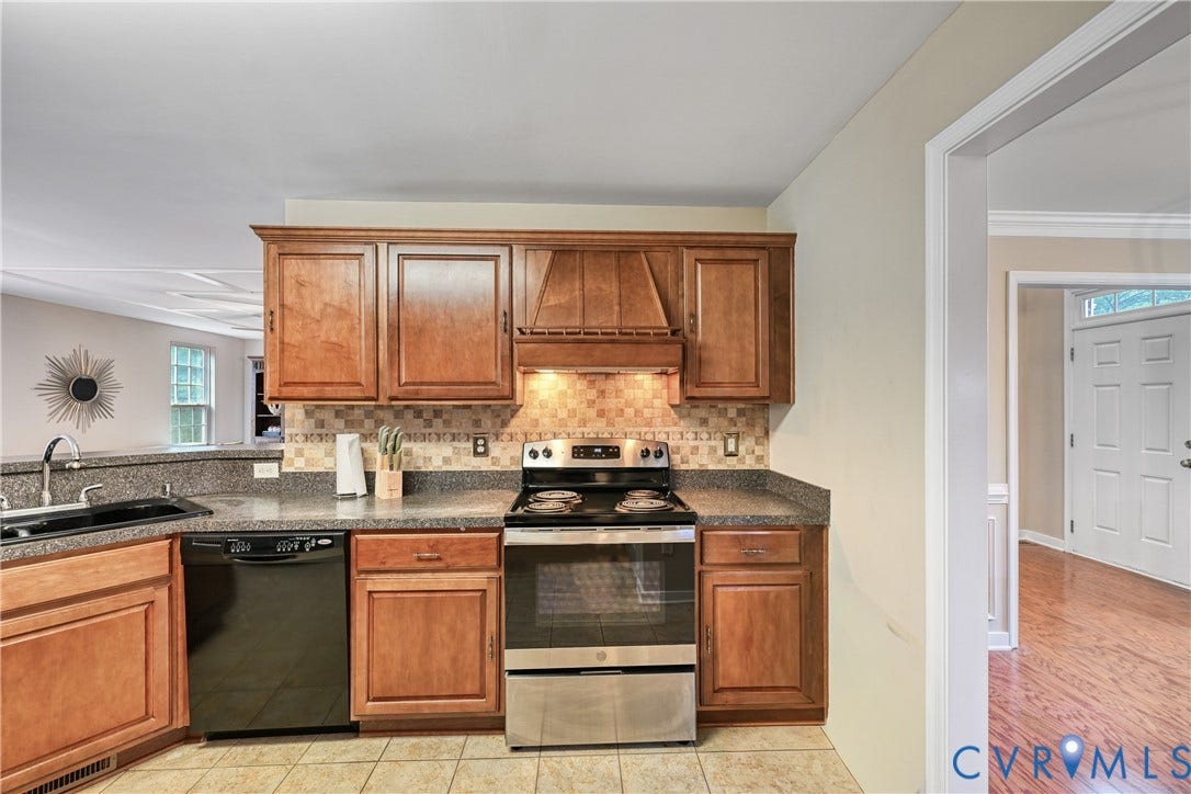 519 N Timber Tribe, Lake Anna, Mineral, VA 23117 Kitchen featuring wood cabinetry, a mosaic tile backsplash, black and stainless steel appliances, a double basin sink, and stone-finish countertops