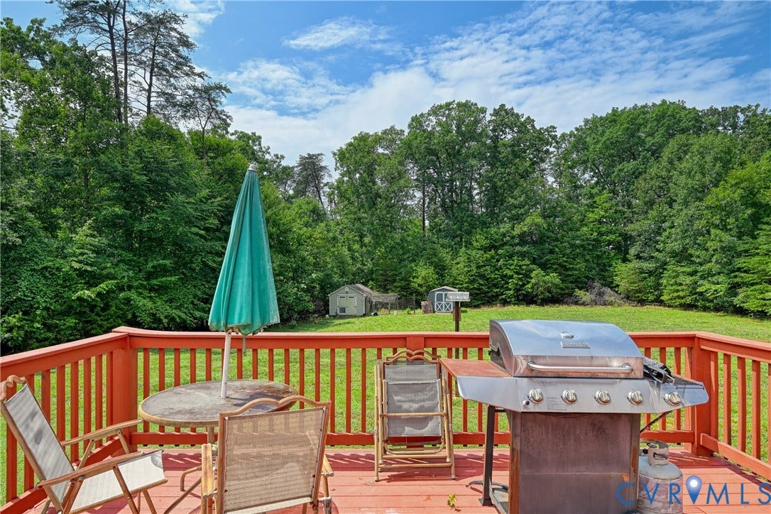 519 N Timber Tribe, Lake Anna, Mineral, VA 23117 Expansive red-stained deck with railing overlooking a generous lawn surrounded by mature trees