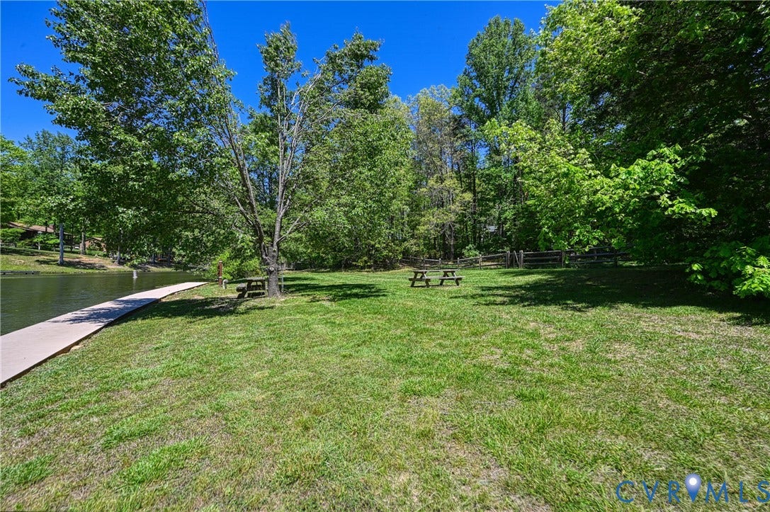519 N Timber Tribe, Lake Anna, Mineral, VA 23117 Expansive grassy yard with mature trees and a concrete path bordering the water