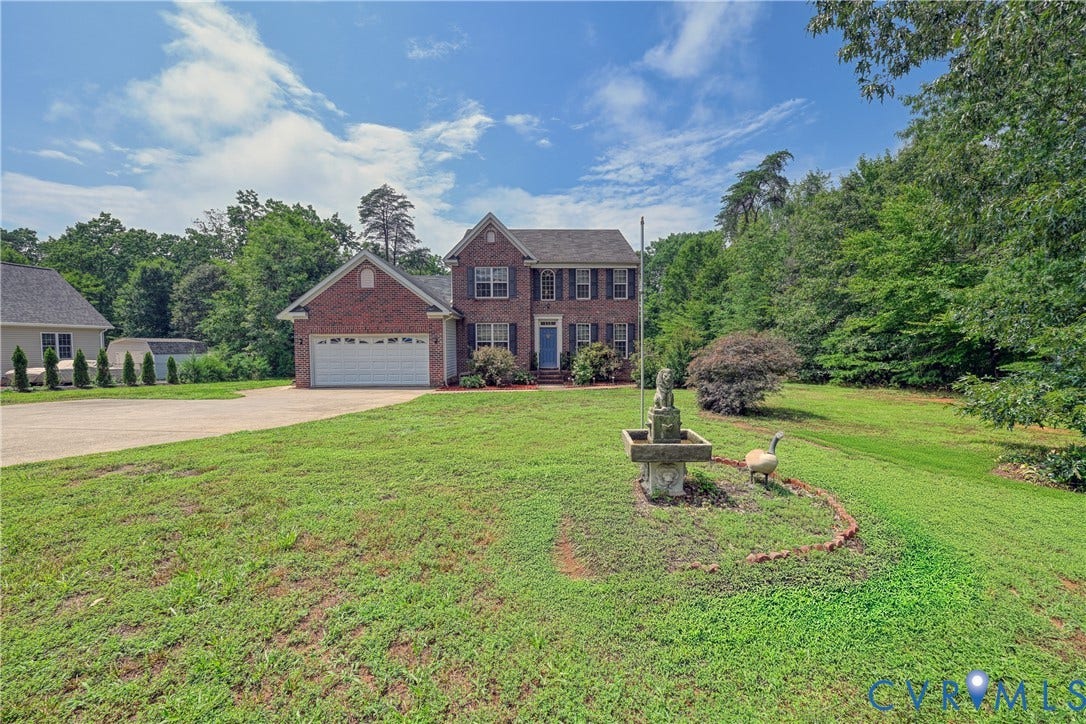 519 N Timber Tribe, Lake Anna, Mineral, VA 23117 Brick two-story colonial-style residence featuring a two-car garage, mature landscaping, and an expansive front lawn