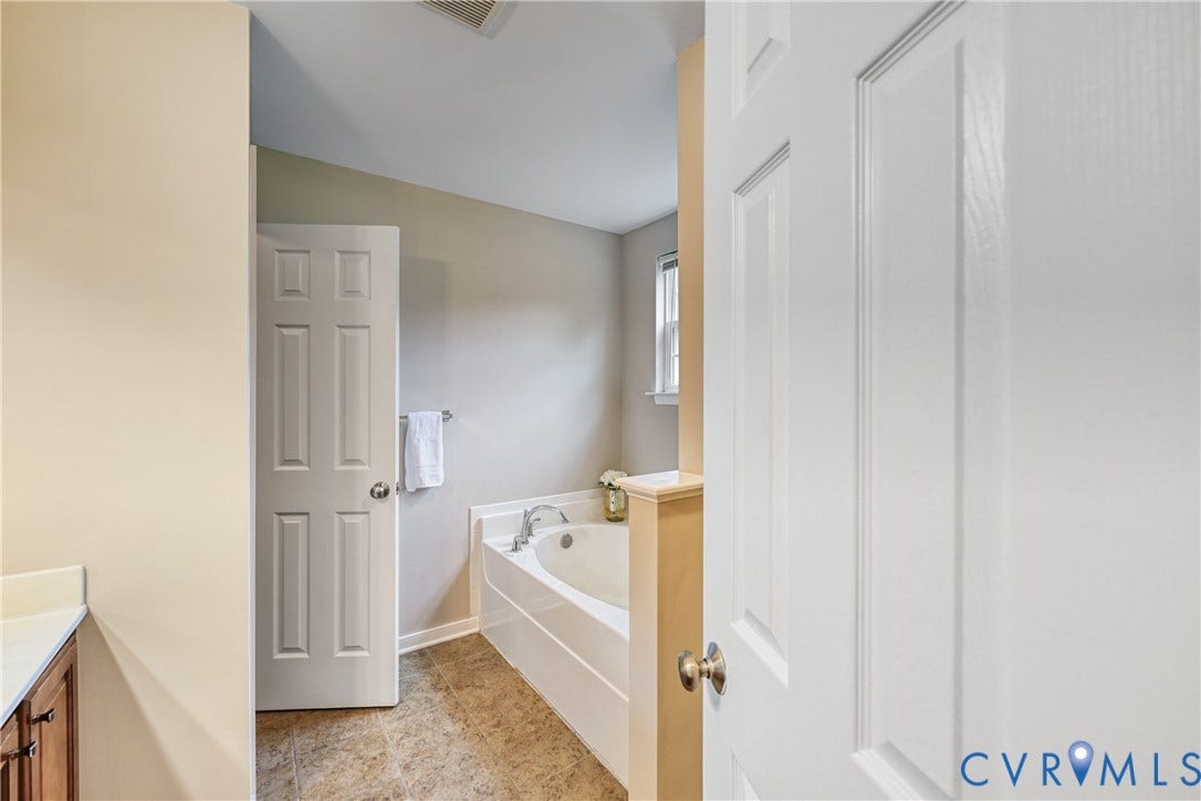 519 N Timber Tribe, Lake Anna, Mineral, VA 23117 Bathroom featuring a built-in tub with deck-mounted fixtures, wood-finish flooring, and a window with trim