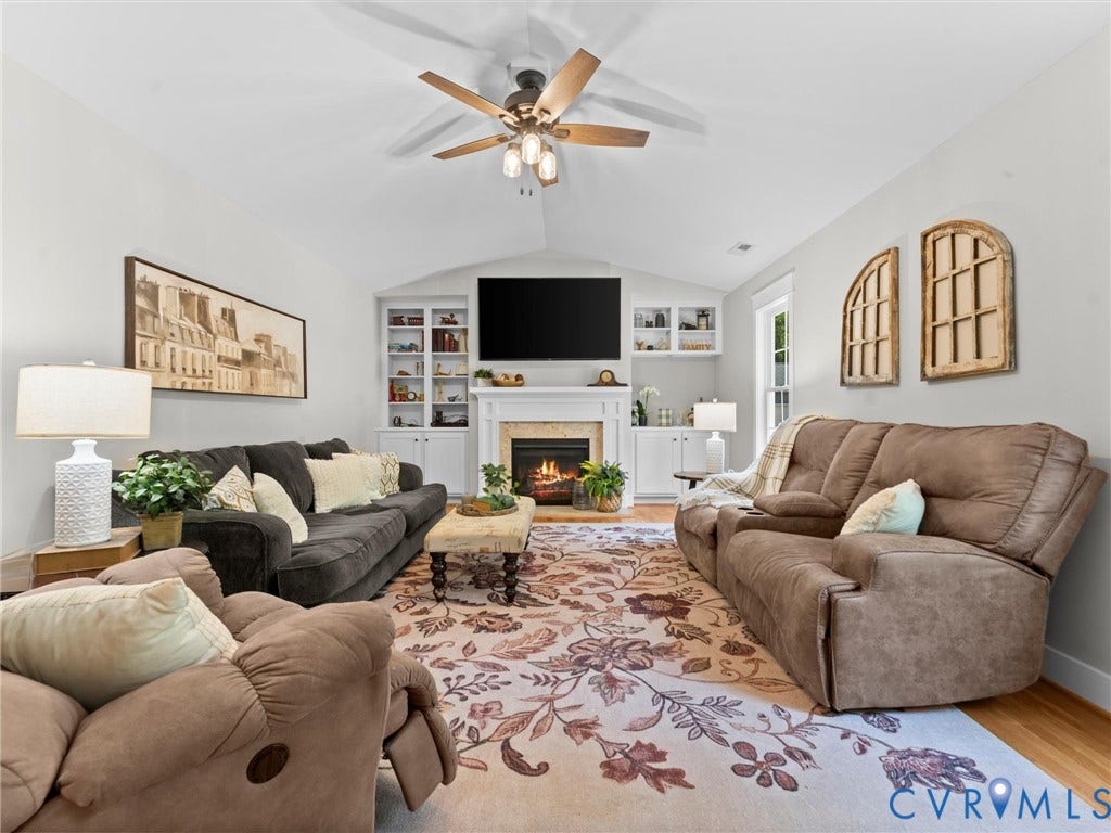 Spacious living area featuring a vaulted ceiling and built-in bookcases