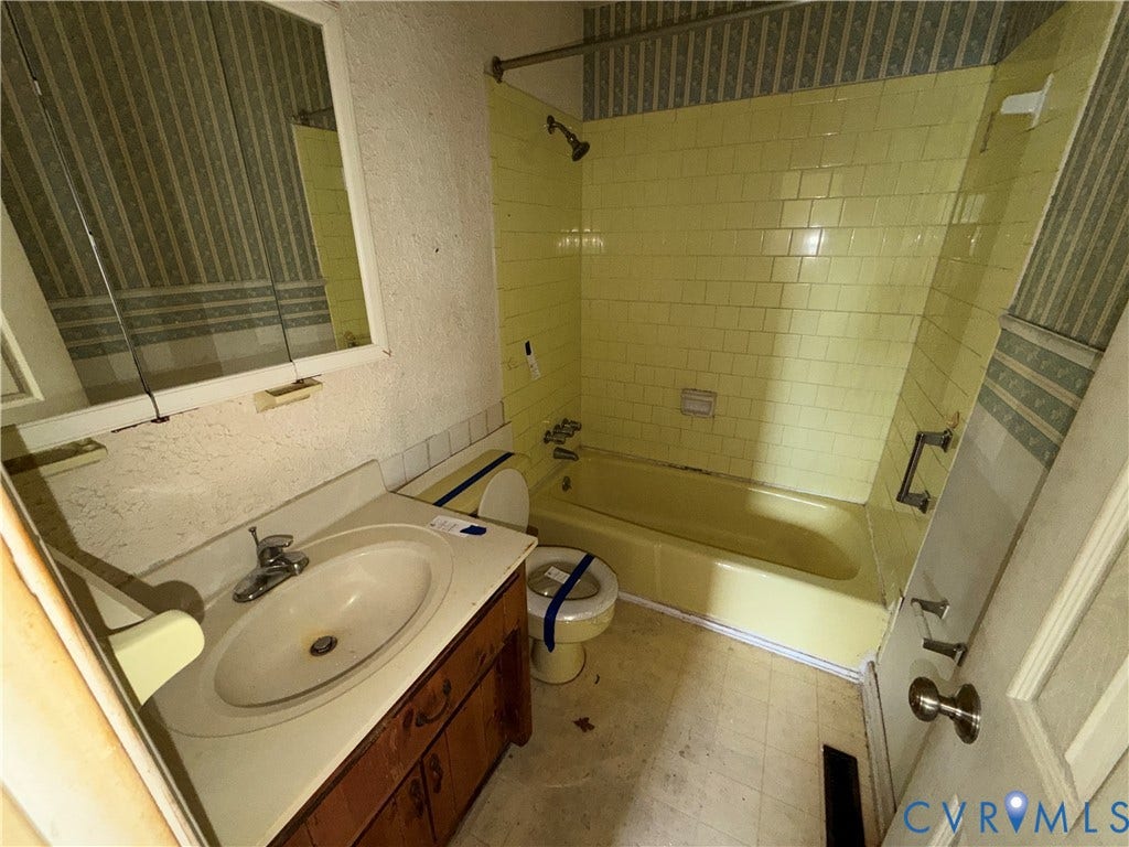 1121 E Booker Circle, Petersburg, VA 23803 Bathroom featuring a vanity with an integrated sink, a wall-mounted mirror, and a bathtub with tiled surround