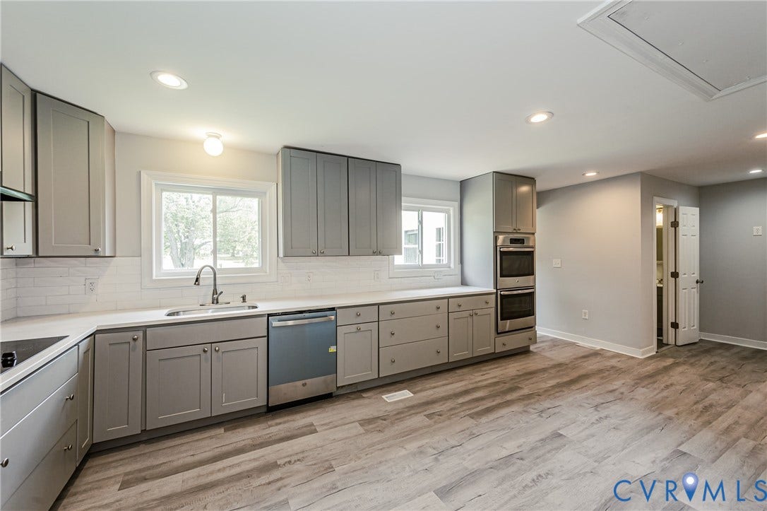 2015 Fordson Road, Richmond, VA 23229 Spacious kitchen featuring extensive gray cabinetry, light countertops, subway tile backsplash, stainless steel double ovens, and wood-finish flooring