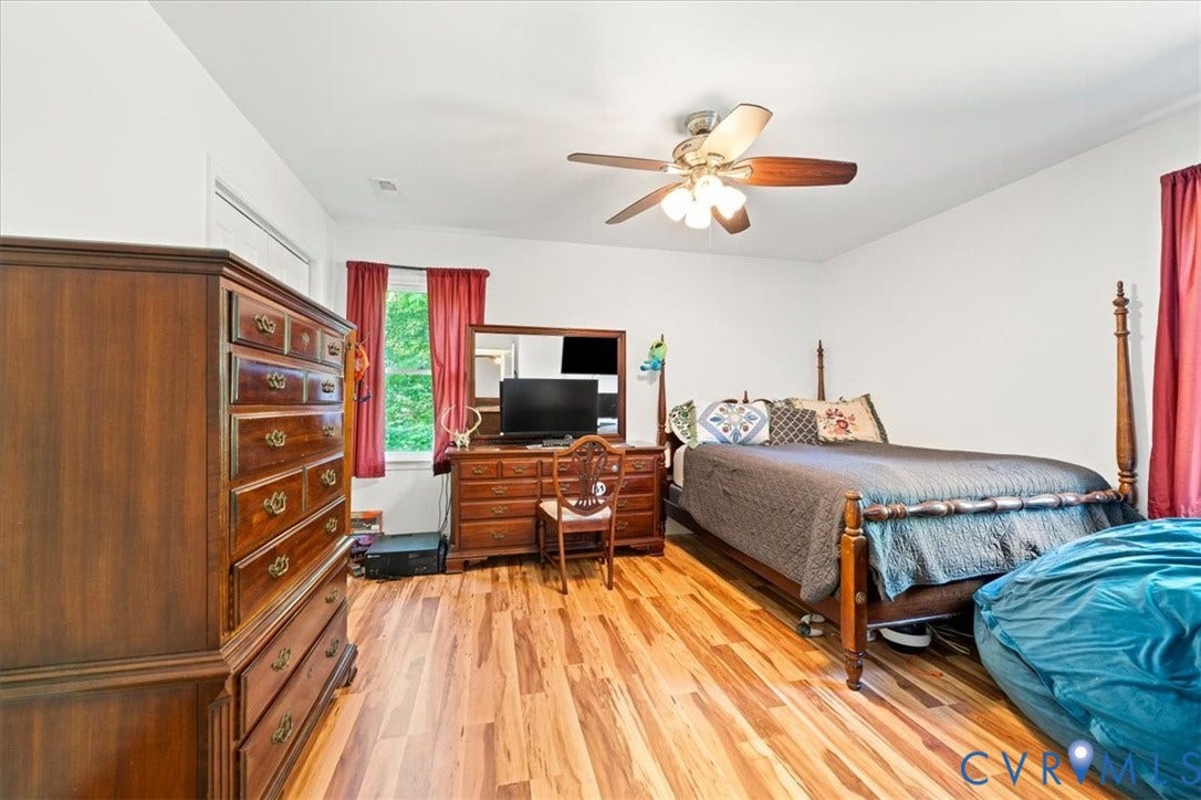 Bright interior space featuring wood-finish flooring, a window with exterior views, and a ceiling fan with integrated lighting