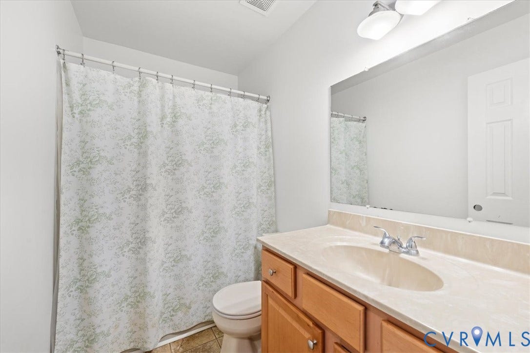 Bathroom featuring a light-toned vanity with an integrated sink and chrome faucet, a large wall-mounted mirror, and overhead vanity lighting