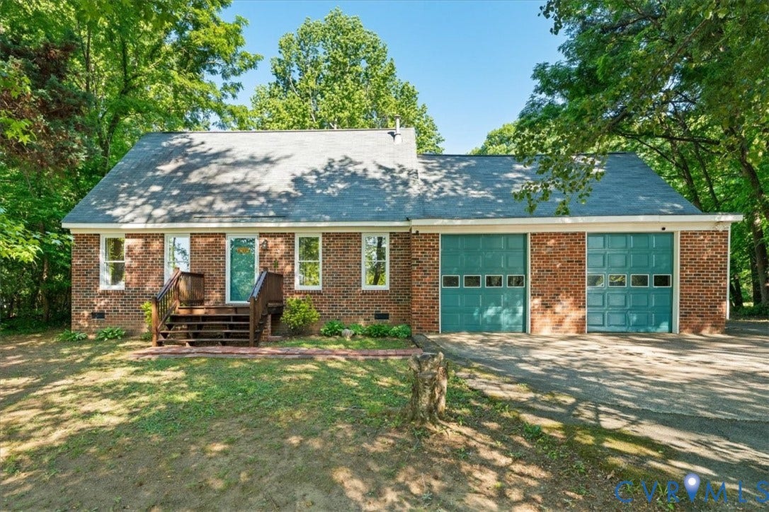 Brick exterior featuring a gabled roof and a prominent two-car garage with teal sectional doors