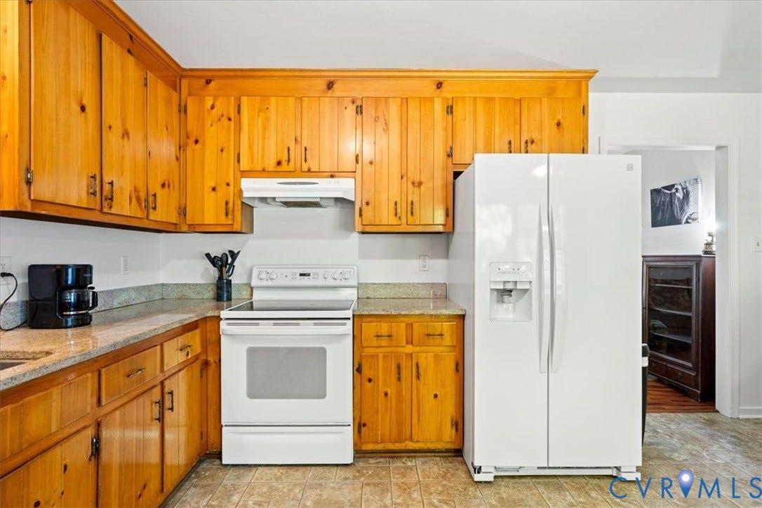 Kitchen featuring wood cabinetry, solid surface countertops, white range, and a white side-by-side refrigerator with dispenser