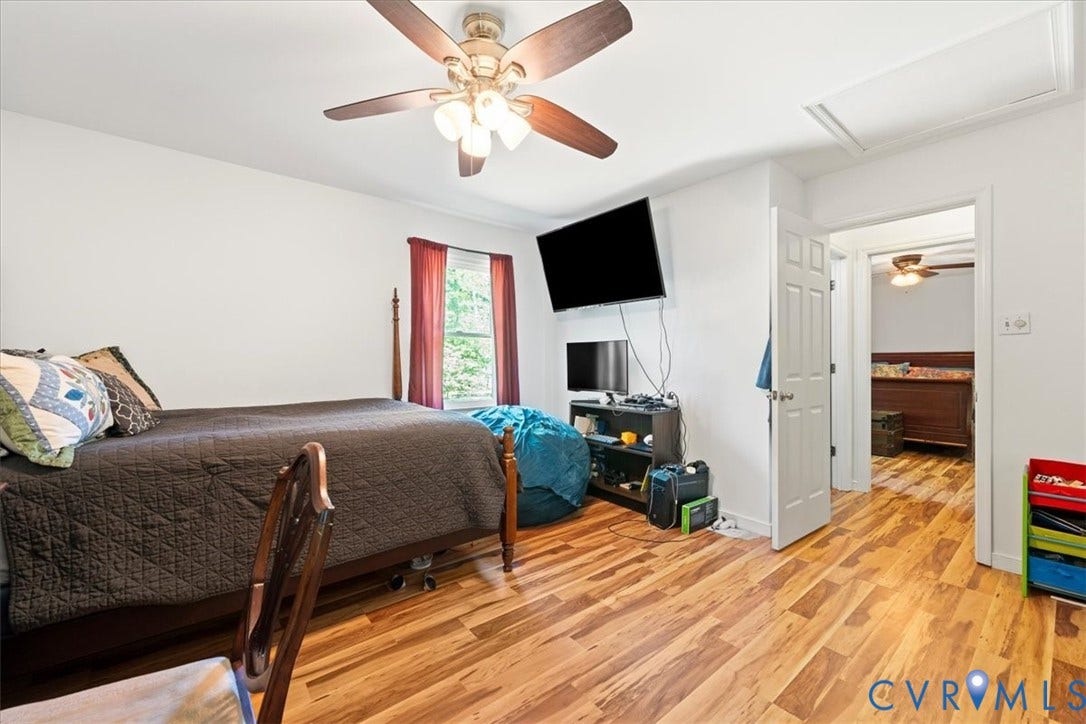Room featuring wood-finish flooring, a ceiling fan with integrated lighting, a single window, and a white interior door