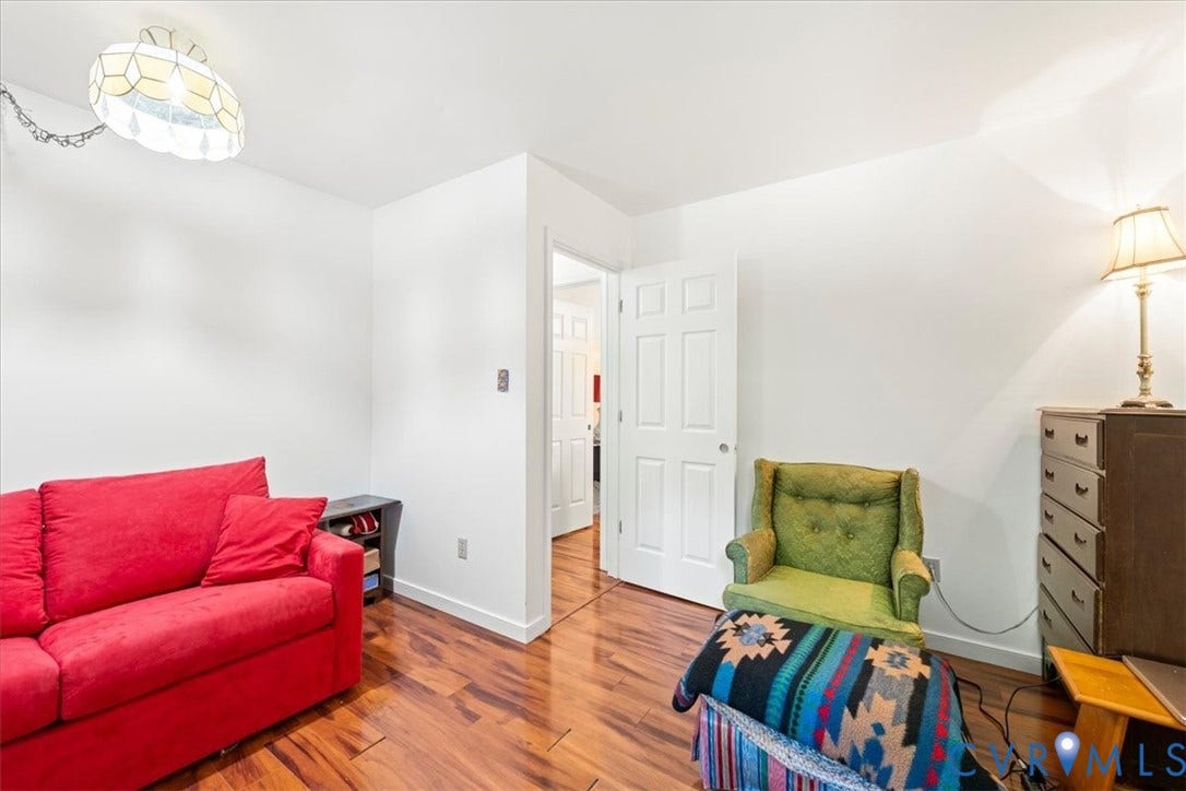 Interior space featuring wood-finish flooring, white painted walls, and a multi-panel interior door