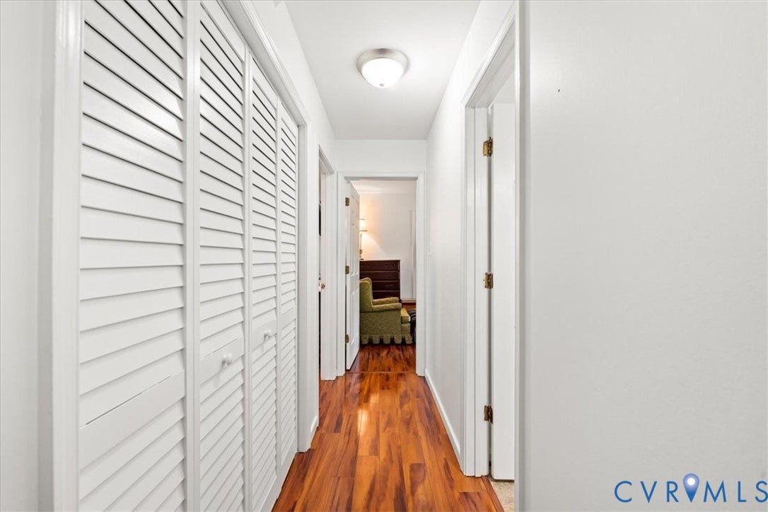 Hallway featuring wood-finish flooring, white louvered bifold doors, and recessed ceiling lighting