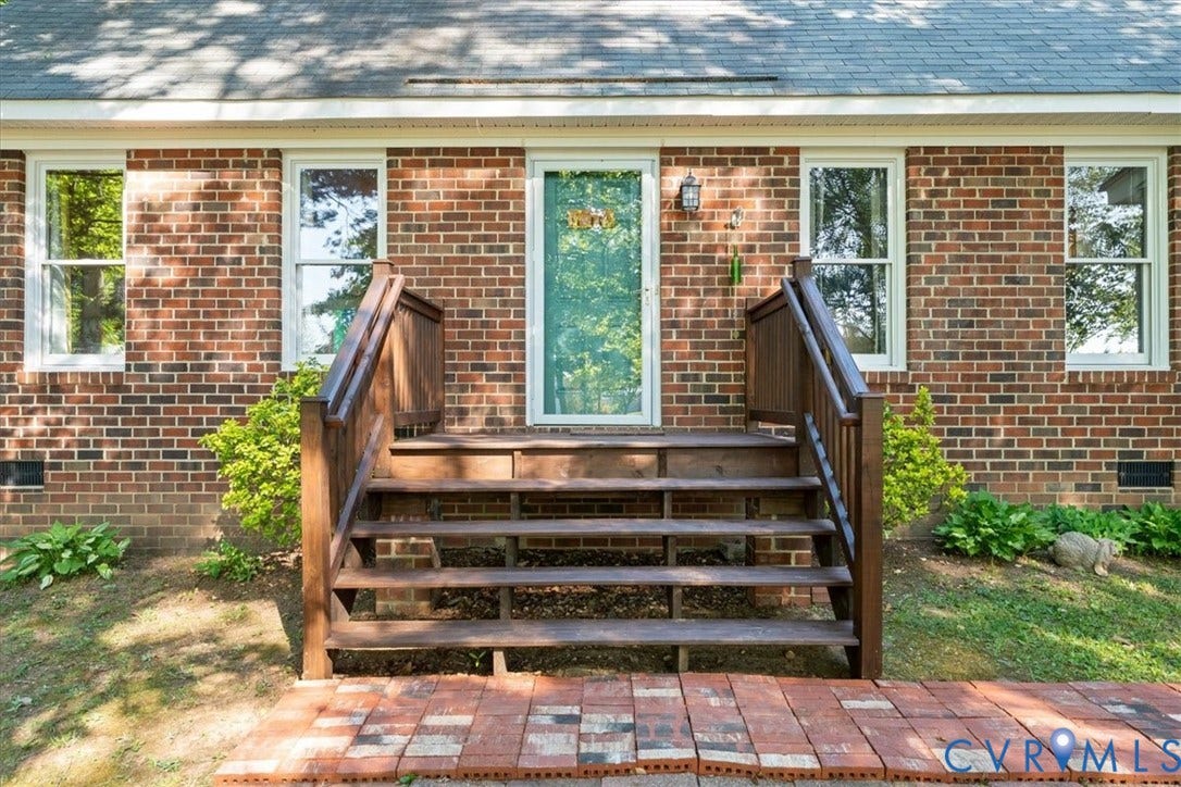 Brick facade with a white storm door and two white-framed windows