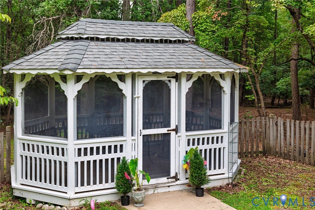 14301 Creek Stone Drive, Chesterfield, VA 23838 White screened gazebo featuring a tiered roof with grey shingles, decorative arch supports, and a slatted lower railing