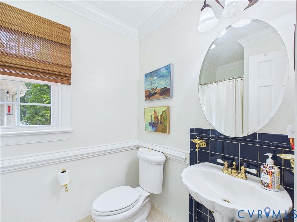 14301 Creek Stone Drive, Chesterfield, VA 23838 Bathroom featuring a pedestal sink with brass-finish fixtures, a dark tiled backsplash, and an oval wall mirror