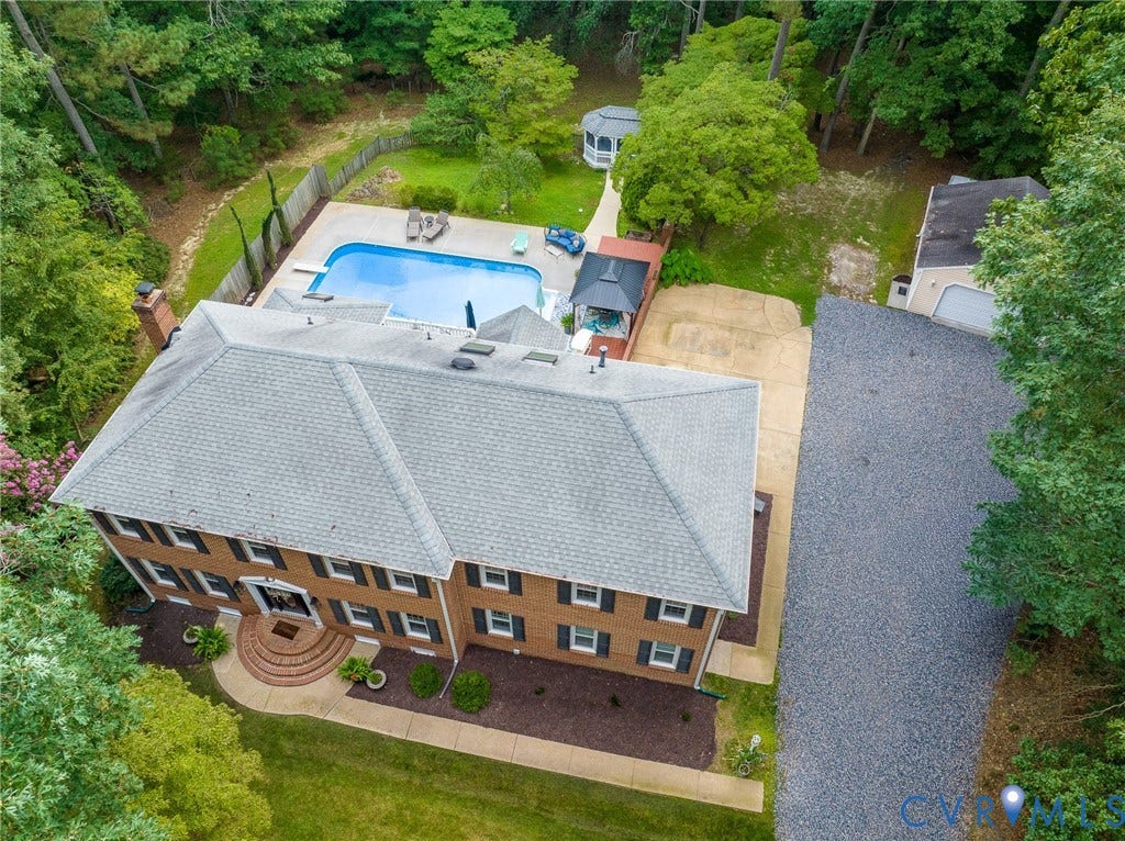 14301 Creek Stone Drive, Chesterfield, VA 23838 Two-story brick residence featuring a gray shingle roof, a fenced backyard with an in-ground swimming pool, a detached garage, and a gravel driveway