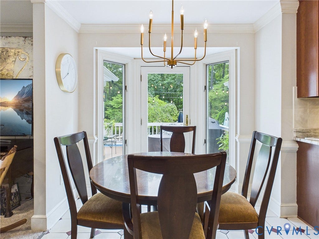 14301 Creek Stone Drive, Chesterfield, VA 23838 Dining area featuring a brass chandelier, a bay window with multiple glass-paned doors, crown molding, and a tiled floor with a geometric pattern