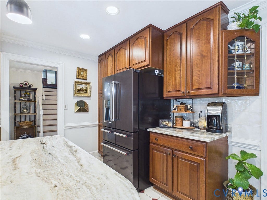 14301 Creek Stone Drive, Chesterfield, VA 23838 Kitchen featuring a large central island with a light-toned, variegated stone countertop, floor-to-ceiling wood cabinetry, a built-in refrigerator, and a tiled backsplash