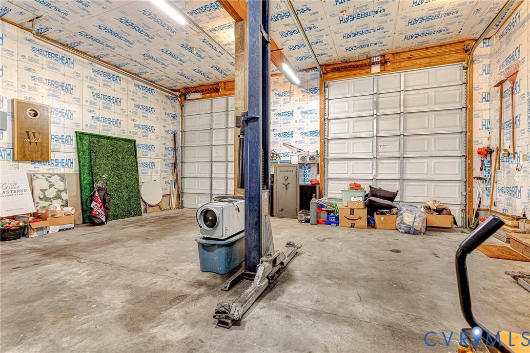 348 Forest Lane, Timberland Estates, King William, VA 23086 Spacious garage featuring concrete flooring, insulated walls and ceiling, dual roll-up garage doors, and overhead strip lighting