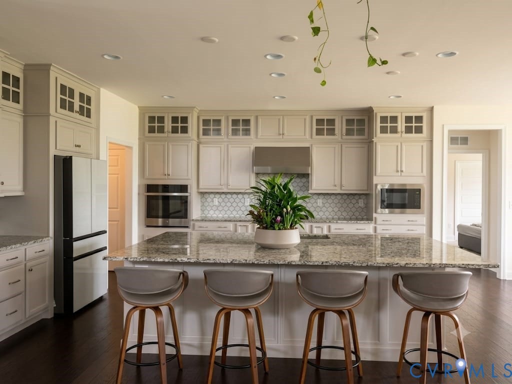 18037 Bay Point Way, Moseley, VA 23120 Spacious kitchen featuring an expansive island with a polished stone countertop, white shaker cabinetry, stainless steel appliances, and dark wood-finish flooring