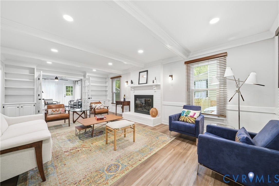 Spacious living area featuring wood-finish flooring, a white brick fireplace with mantel, and recessed lighting