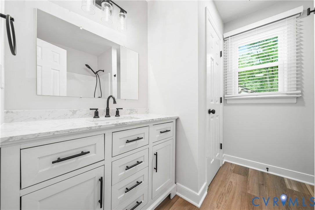 Modern bathroom vanity featuring a white countertop with integrated sink and matte black faucet
