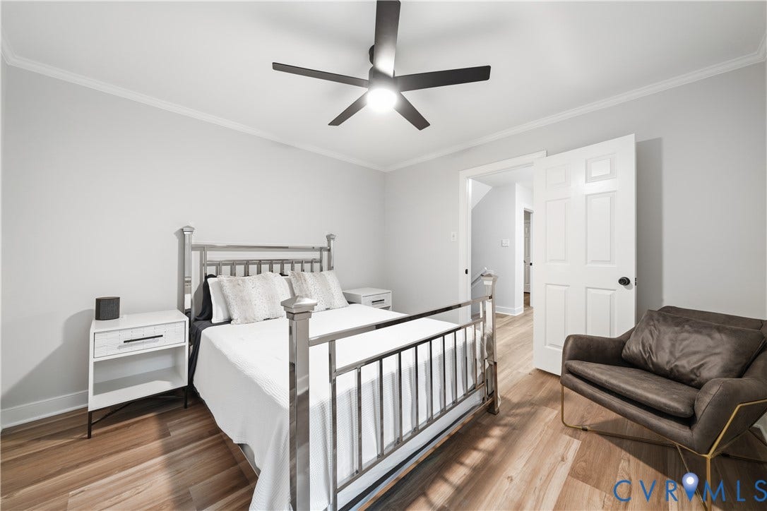 Room featuring light wood-finish flooring, white crown molding, and a ceiling fan with integrated lighting