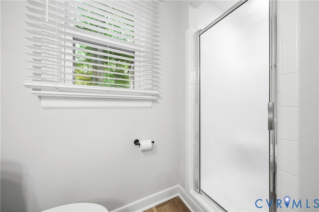 Shower enclosure with frosted glass and chrome framing, surrounded by white subway tile
