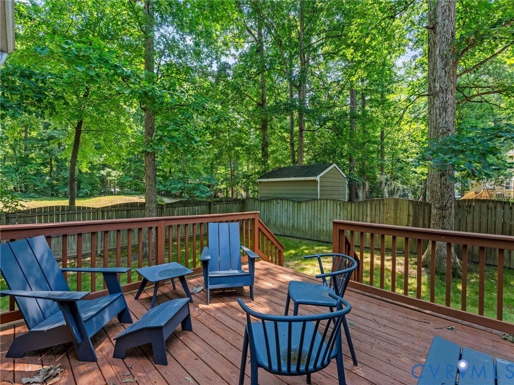 Spacious wood-finish deck with railing, stairs, and mature tree canopy overhead