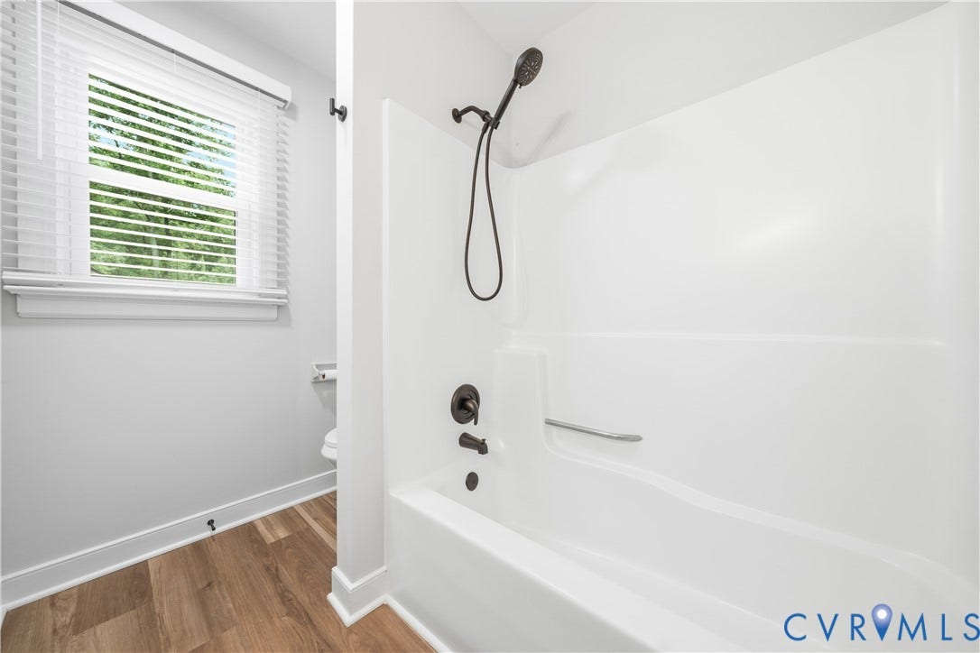 White fiberglass tub and shower combination with oil-rubbed bronze fixtures