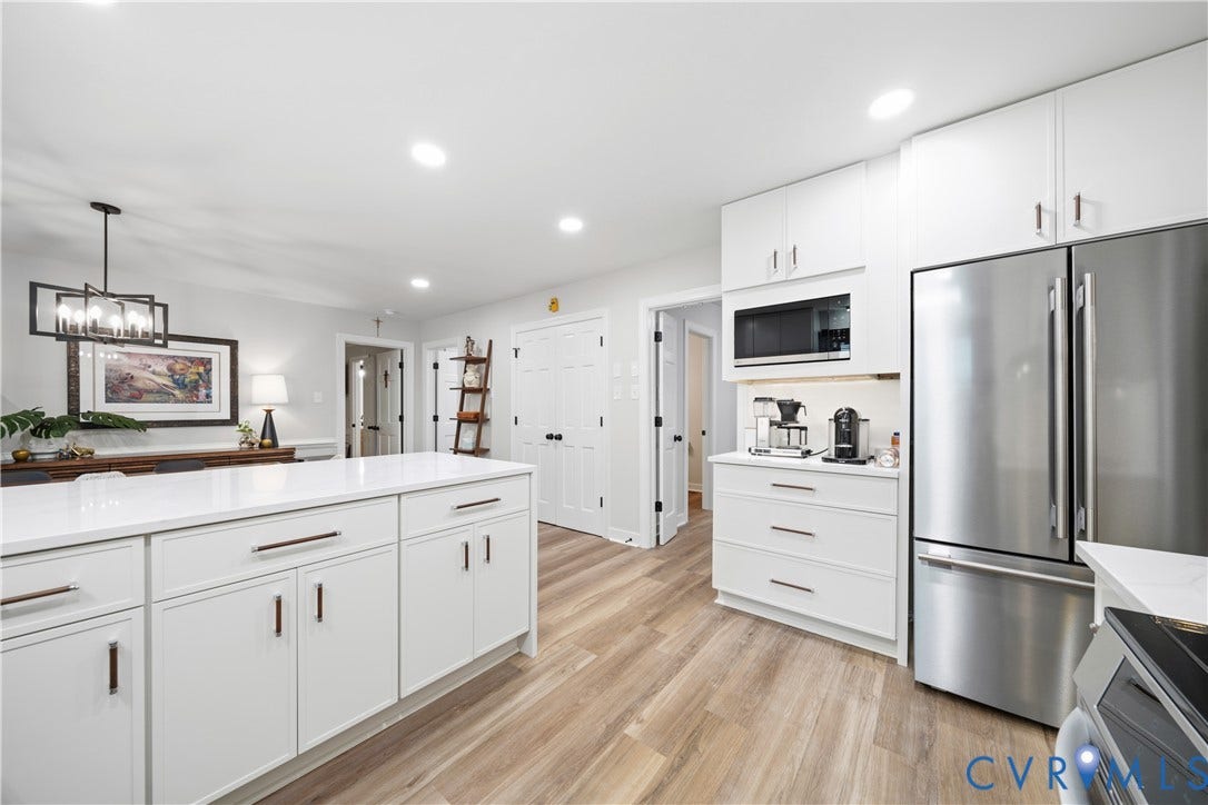 Contemporary kitchen featuring a large central island with white cabinetry and a light-toned countertop