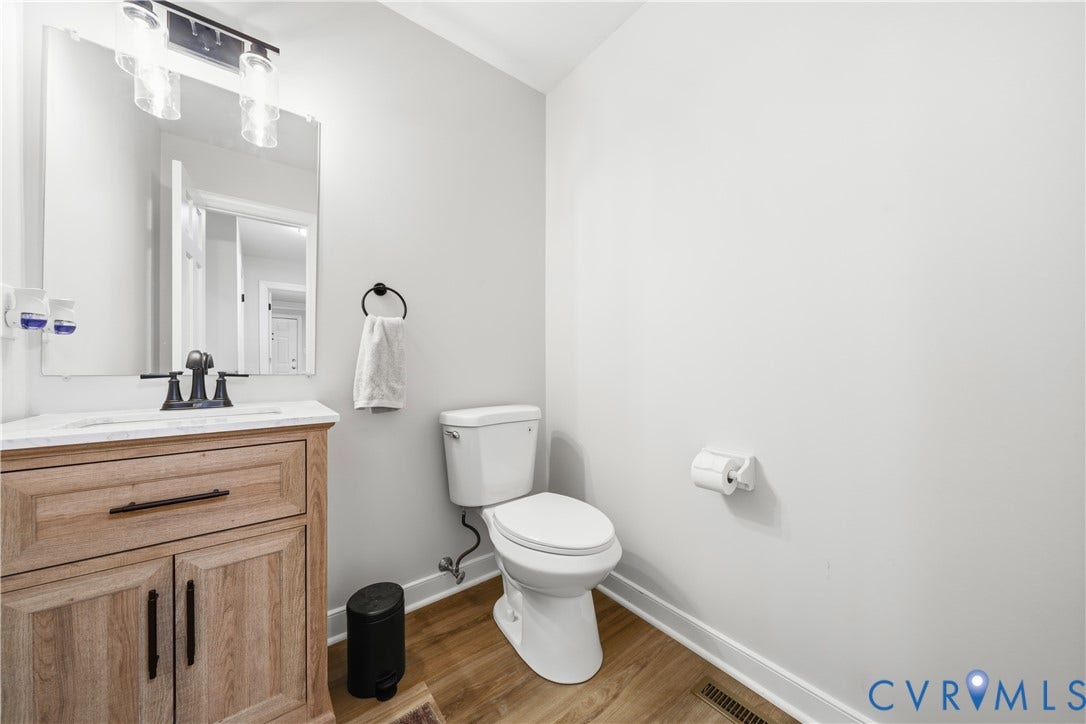 Bathroom featuring a wood-finish vanity with a light-toned countertop, rectangular sink, and matte black faucet