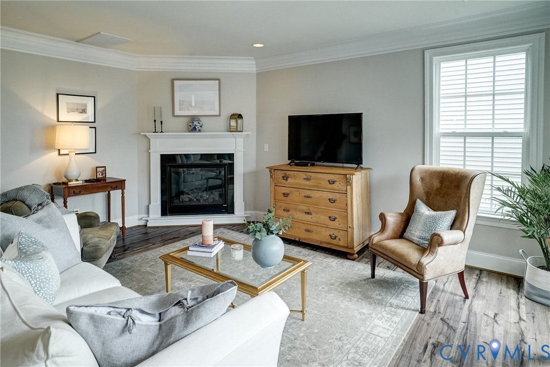 18024 Twin Falls Lane, Aston Oaks, Moseley, VA 23120 Living area featuring a white mantel fireplace with a dark surround, crown molding, wood-finish flooring, and a window with white blinds