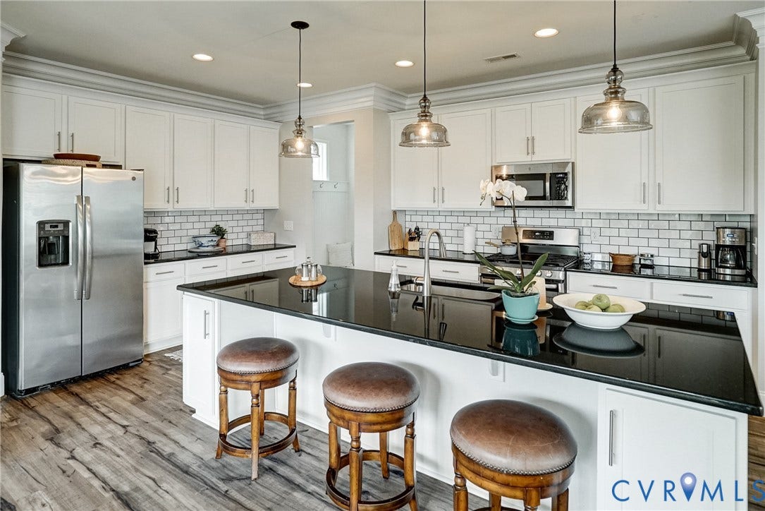 18024 Twin Falls Lane, Aston Oaks, Moseley, VA 23120 Kitchen featuring a central island with a dark countertop, white perimeter cabinetry, stainless steel appliances, and wood-finish flooring