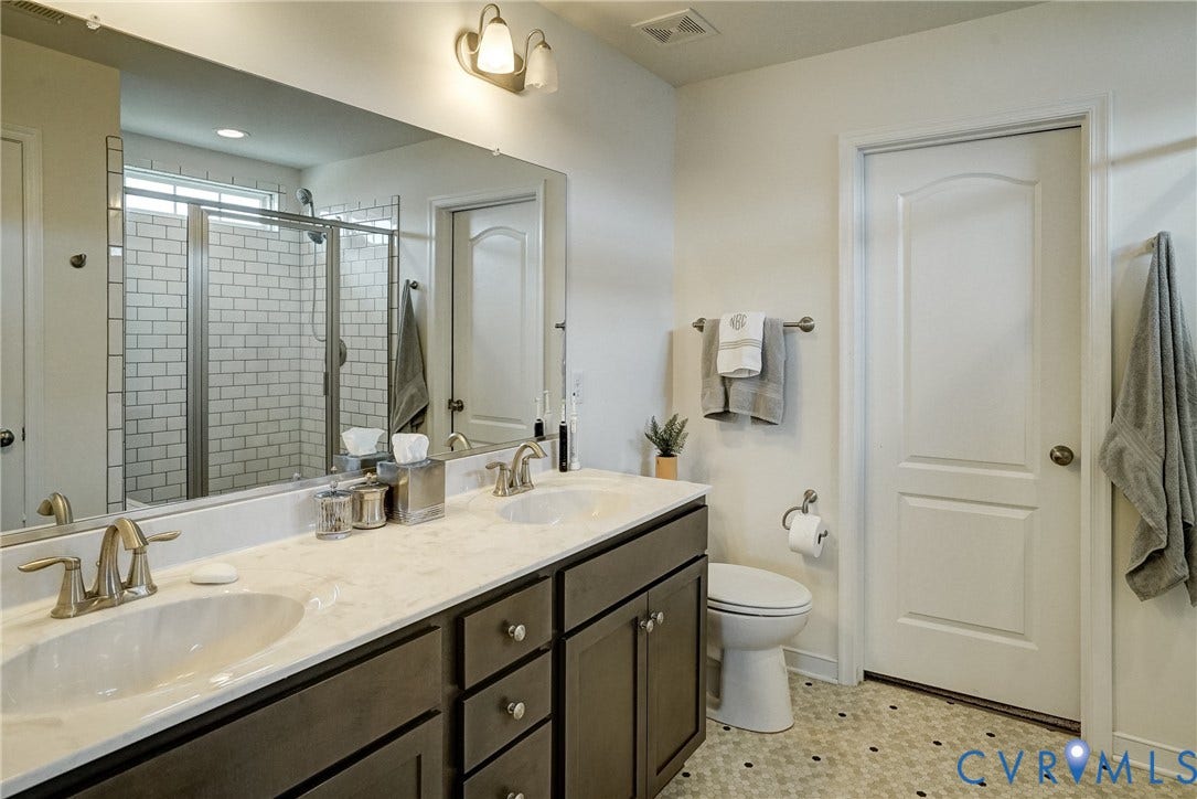 18024 Twin Falls Lane, Aston Oaks, Moseley, VA 23120 Bathroom featuring a dual vanity with a light-toned countertop, two integrated sinks, and dark cabinetry