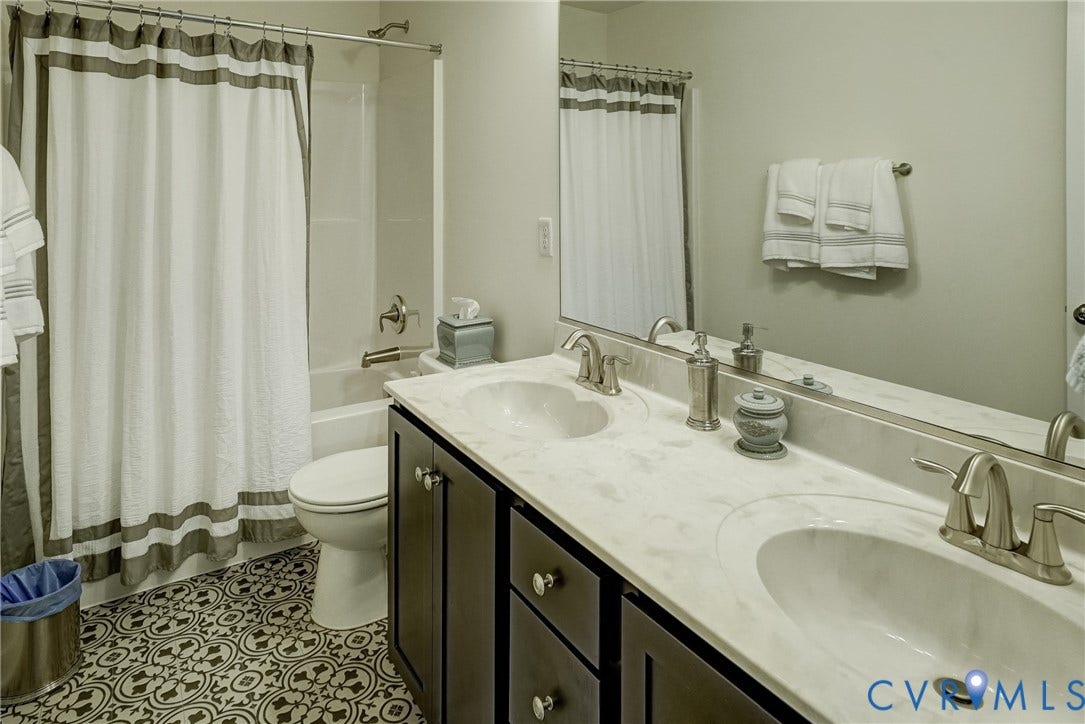 18024 Twin Falls Lane, Aston Oaks, Moseley, VA 23120 Double vanity with an integrated countertop and undermount sinks, bronze finish hardware, and patterned floor tile