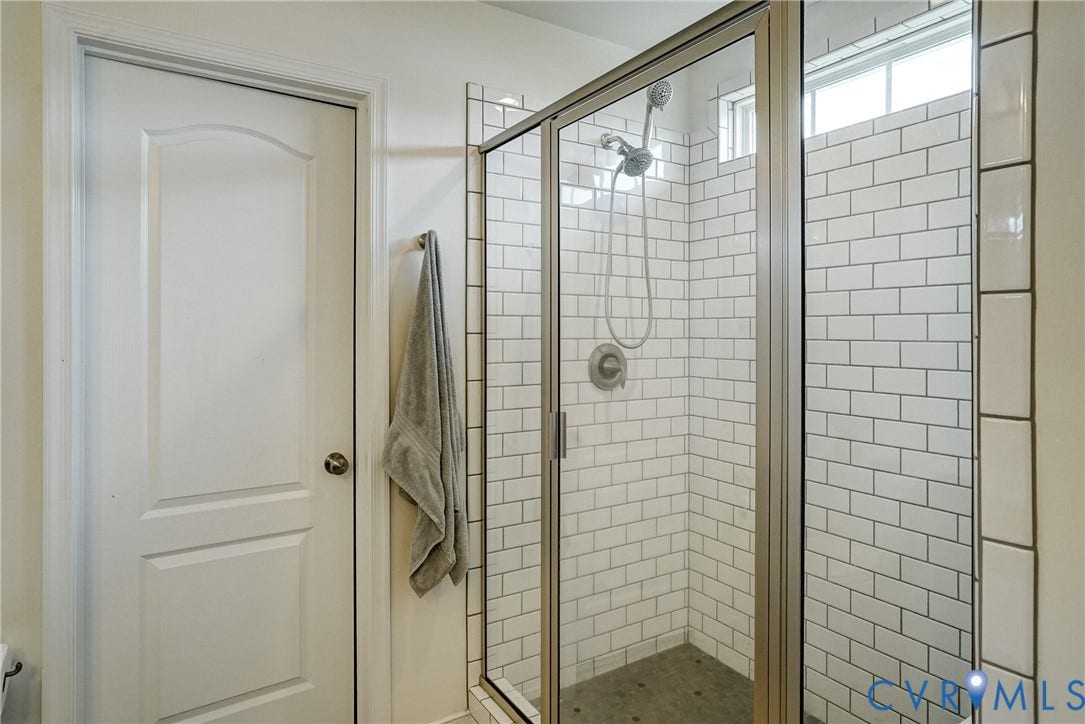 18024 Twin Falls Lane, Aston Oaks, Moseley, VA 23120 Shower enclosure featuring a frameless glass door, subway tile surround, textured floor, and a satin nickel shower head