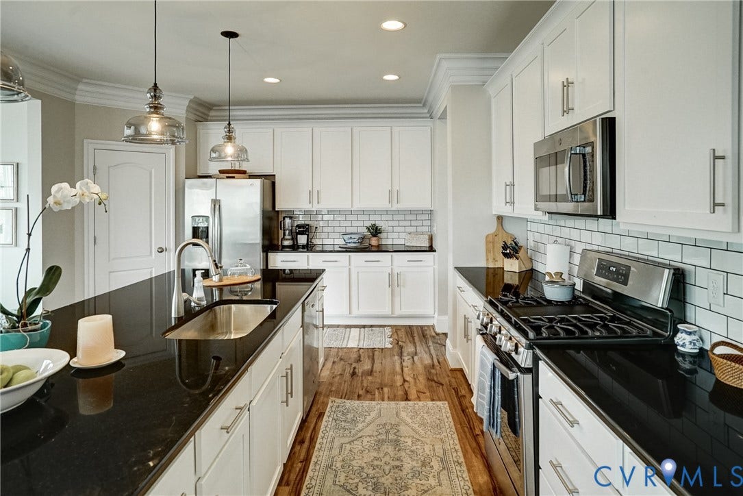 18024 Twin Falls Lane, Aston Oaks, Moseley, VA 23120 Kitchen featuring a dark stone-finish island with an undermount sink, stainless steel appliances, white cabinetry, subway tile backsplash, and wood-finish flooring