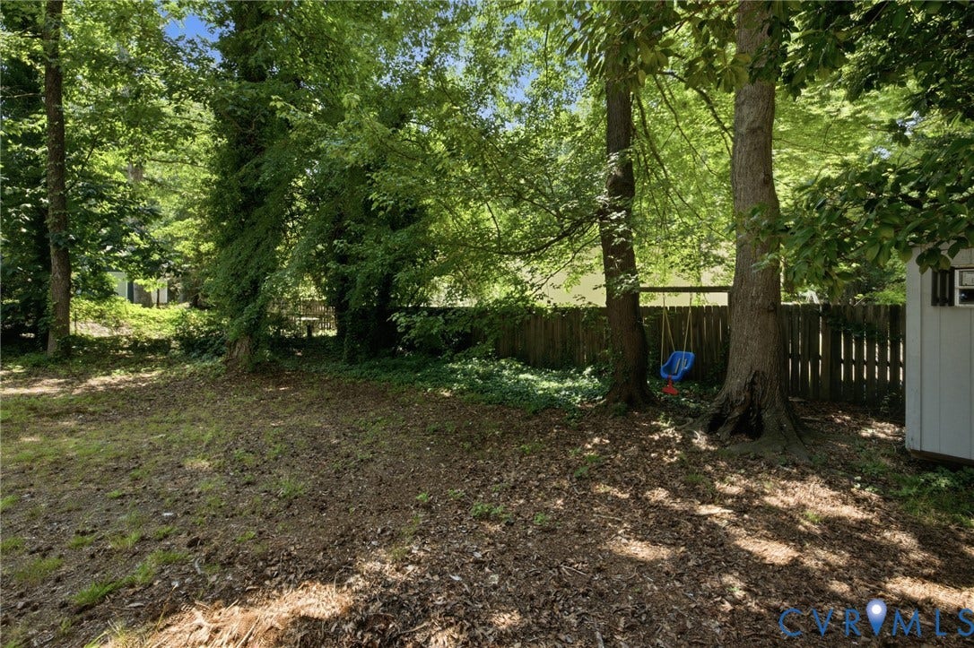 3224 Wyntrebrooke Drive, North Chesterfield, VA 23235 Spacious backyard featuring mature trees, a wood privacy fence, and a light-colored storage shed with dark shutters
