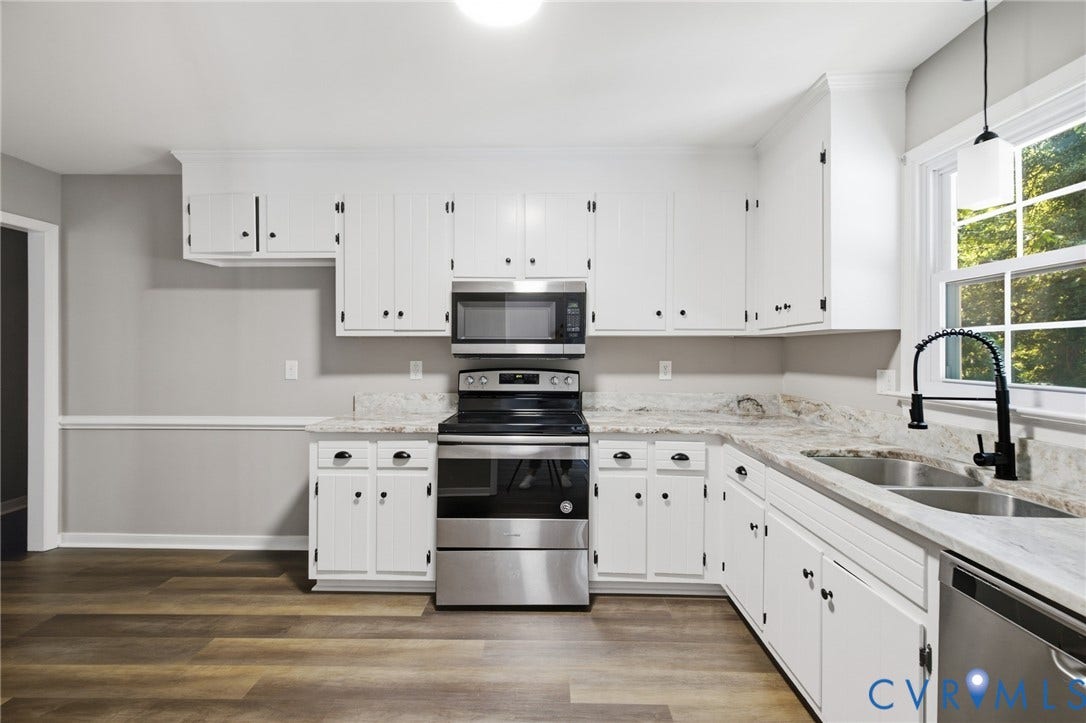 3224 Wyntrebrooke Drive, North Chesterfield, VA 23235 Kitchen featuring wood-finish flooring, white cabinetry with black hardware, light-toned countertops, and stainless steel appliances including a range, microwave, and dishwasher