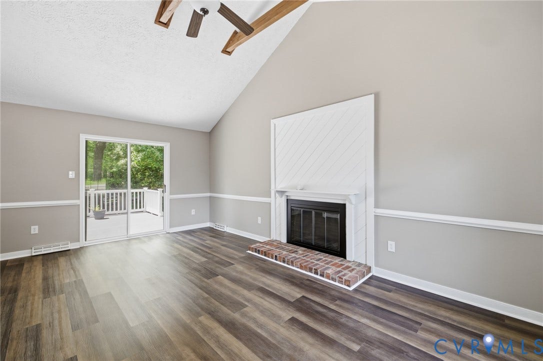 3224 Wyntrebrooke Drive, North Chesterfield, VA 23235 Living space featuring wood-finish flooring, a vaulted ceiling, and a fireplace with a brick hearth and white shiplap-style surround