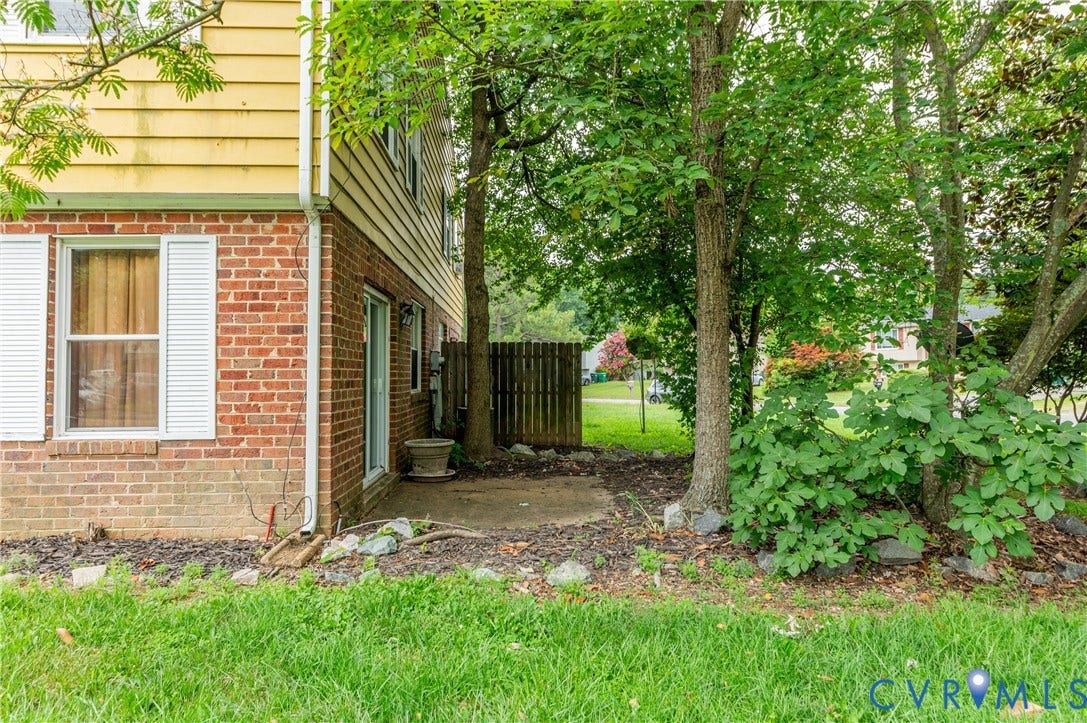 908 Winterstick Place, Highland Springs, VA 23223 Exterior featuring brick and yellow siding, a white-framed window with shutters, and a concrete patio