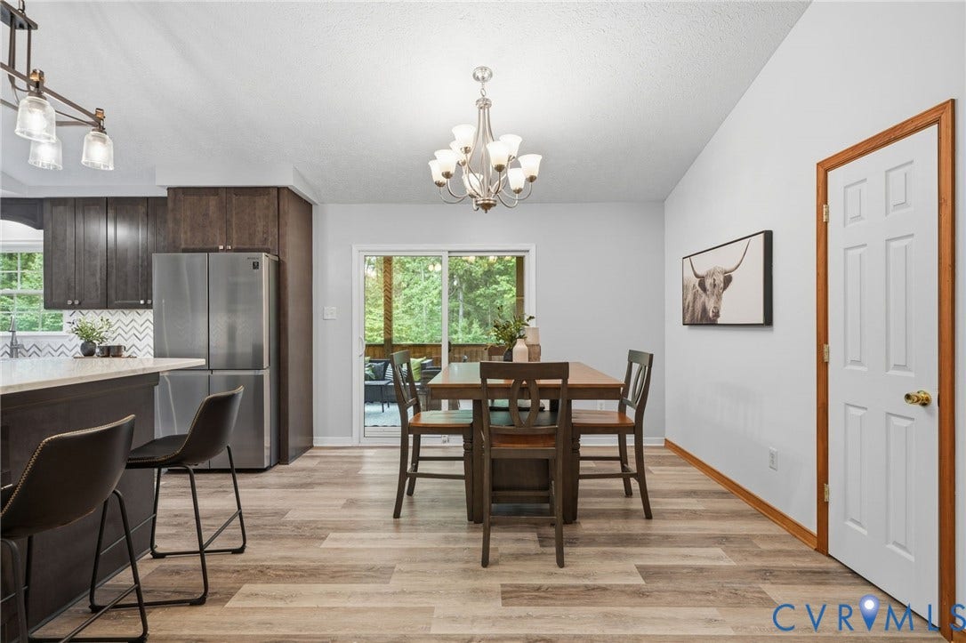 2231 Red Lane Road, Powhatan, VA 23139 Open-concept dining area is perfect for gathering w/family & friends, featuring an updated chandelier, a convenient pantry, & sliding glass doors that seamlessly connect indoor living to the outdoors.