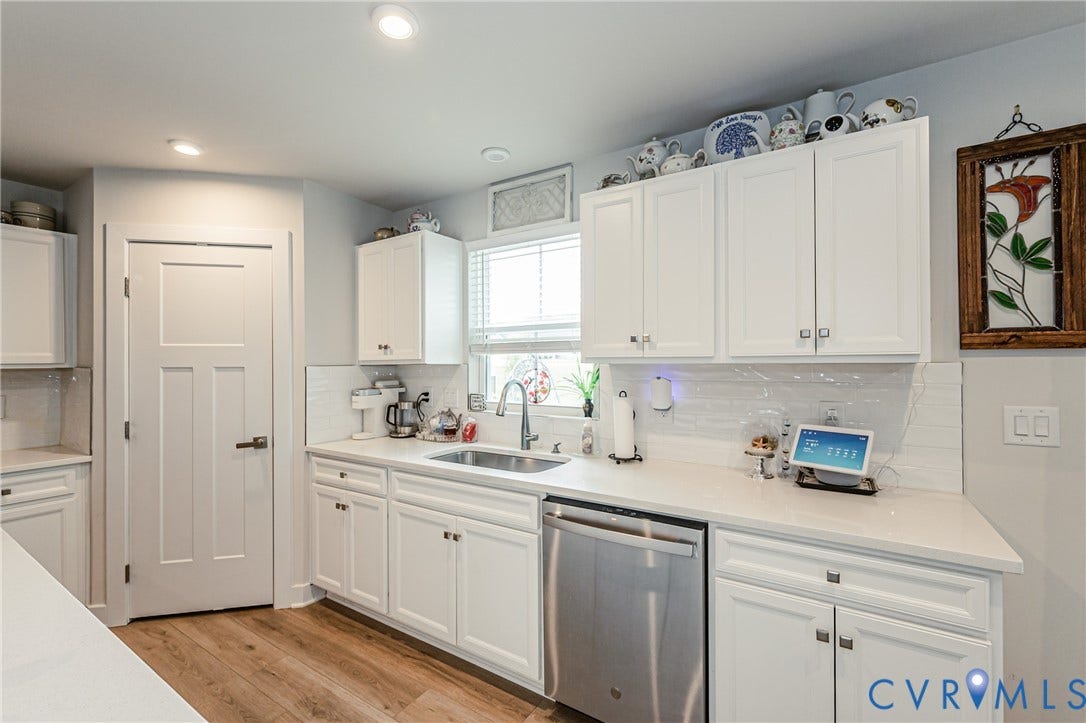 7627 E Danube Loop, New Kent, VA 23124 Bright kitchen with white shaker-style cabinetry, stainless steel dishwasher, undermount sink, and wood-finish flooring