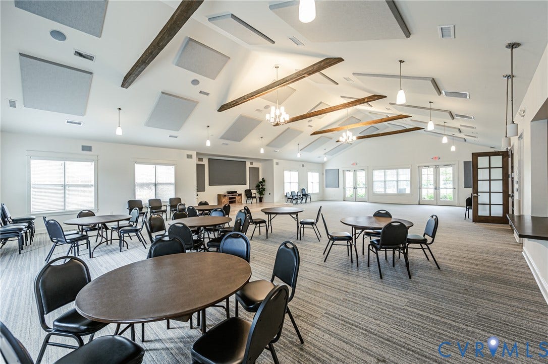 7627 E Danube Loop, New Kent, VA 23124 Spacious multi-purpose room featuring a vaulted ceiling with exposed wood beams, suspended acoustic panels, and contemporary pendant lighting