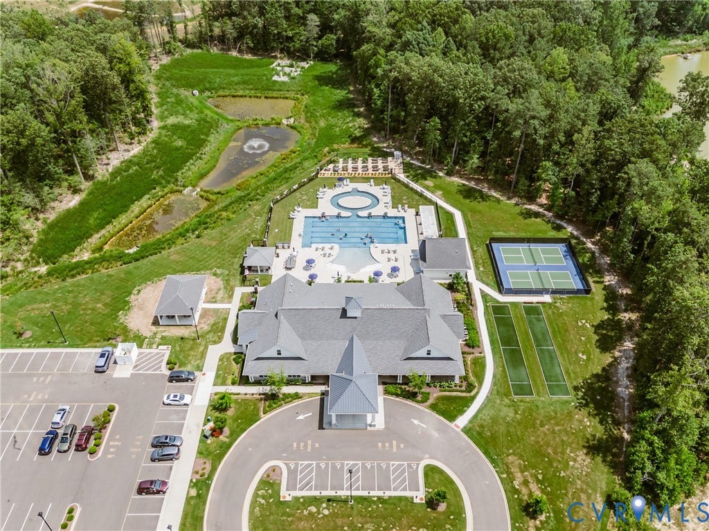 7627 E Danube Loop, New Kent, VA 23124 Aerial view showcasing the community clubhouse, multiple swimming pools, two tennis courts, and two bocce ball courts