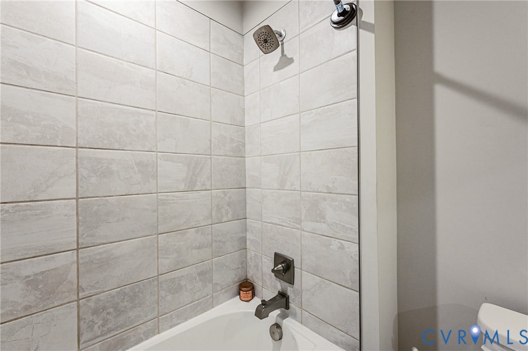 7627 E Danube Loop, New Kent, VA 23124 Bathtub and shower combination featuring light-toned tile surround, a chrome showerhead, and coordinating bath fixtures