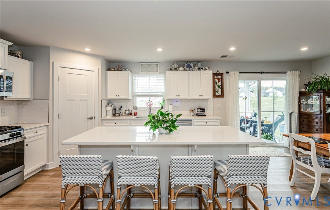 7627 E Danube Loop, New Kent, VA 23124 Spacious kitchen featuring a large central island with seating, white shaker cabinetry, stainless steel appliances, and wood-finish flooring