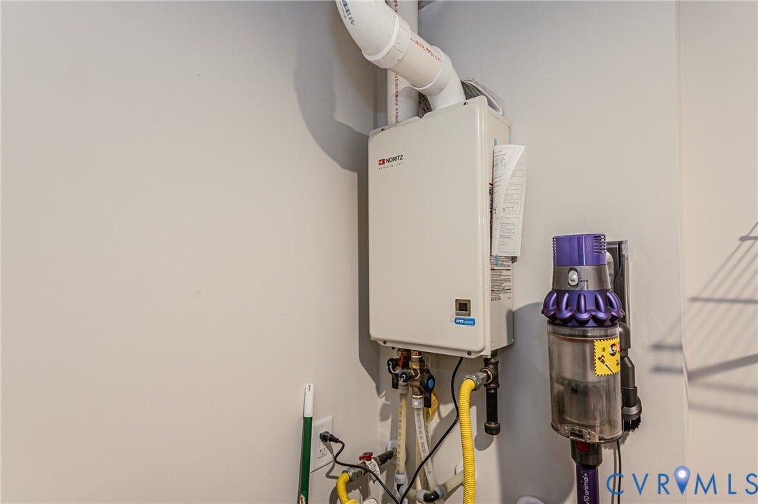 7627 E Danube Loop, New Kent, VA 23124 Wall-mounted tankless water heater with visible gas lines and PVC venting