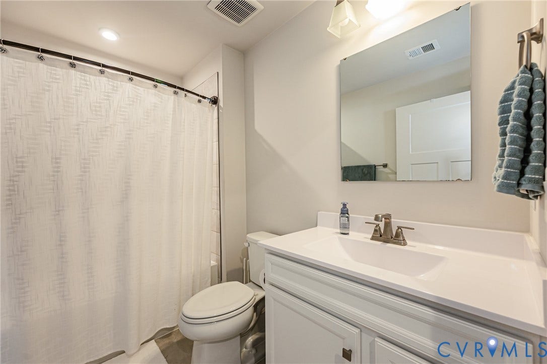 7627 E Danube Loop, New Kent, VA 23124 Bathroom featuring a white vanity with integrated sink, brushed nickel faucet, wall-mounted mirror, and overhead lighting